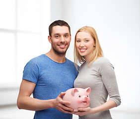 Image showing smiling couple holding big piggy bank