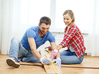 Image showing smiling couple measuring wood flooring