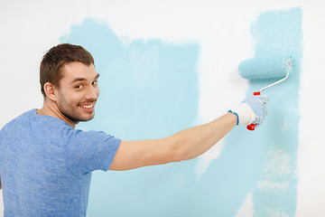 Image showing smiling man painting wall at home