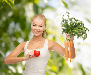 Image showing smiling woman holding heart symbol and carrots