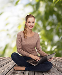 Image showing young woman sitting on floor with laptop
