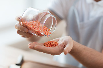 Image showing close up of male emptying jar with red lentils