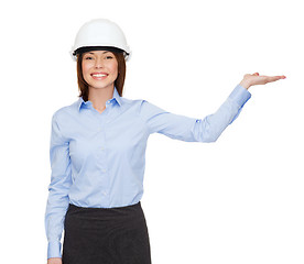 Image showing businesswoman in helmet holding something on palm