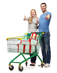 Image showing smiling couple with shopping cart and gift boxes