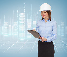 Image showing smiling businesswoman in helmet with clipboard