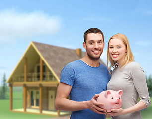 Image showing smiling couple holding big piggy bank