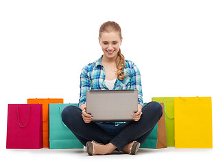 Image showing smiling girl with laptop comuter and shopping bags