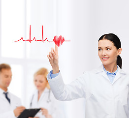 Image showing smiling female doctor pointing to cardiogram