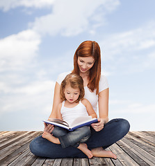 Image showing happy mother with adorable little girl and book