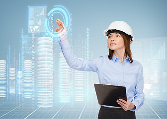 Image showing smiling businesswoman in helmet with clipboard