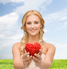 Image showing smiling woman giving small red heart