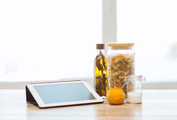 Image showing close up of tablet pc olive oil, pasta and pumpkin