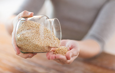 Image showing close up of female emptying jar with quinoa