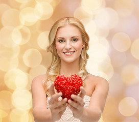 Image showing smiling woman giving small red heart