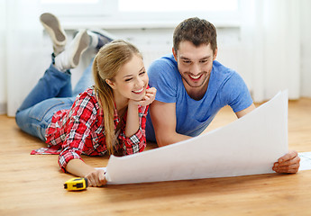 Image showing smiling couple looking at blueprint at home