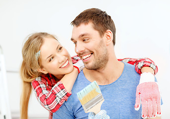 Image showing smiling couple covered with paint with paint brush