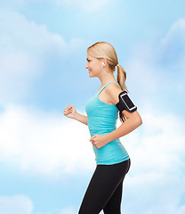 Image showing sporty woman running with smartphone and earphones