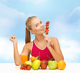 Image showing smiling woman with organic food eating strawberry