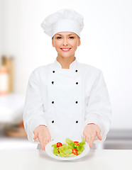 Image showing smiling female chef with salad on plate