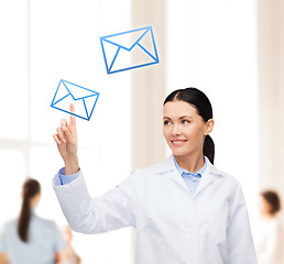 Image showing smiling female doctor pointing to envelope