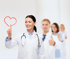 Image showing smiling female doctor pointing to heart