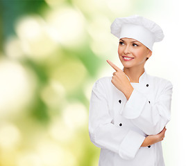 Image showing smiling female chef pointing finger to sonething