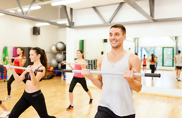 Image showing group of smiling people working out with barbells