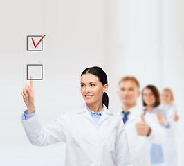 Image showing smiling female doctor pointing checkbox