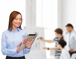 Image showing smiling woman looking at tablet pc at office