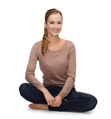 Image showing smiling young woman sitting on floor