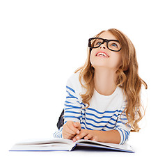 Image showing girl with book and eyeglasses lying on the floor