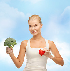 Image showing smiling woman holding heart symbol and broccoli