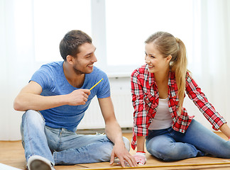 Image showing smiling couple measuring wood flooring