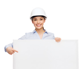 Image showing businesswoman in helmet pointing finger to board