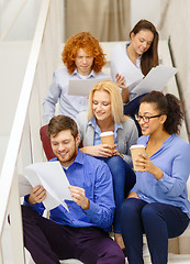 Image showing team with papers and take away coffee on staircase