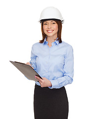 Image showing smiling businesswoman in helmet with clipboard