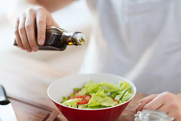 Image showing close up of male hands flavouring salad in a bowl