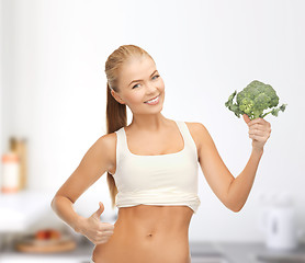 Image showing woman pointing at her abs and holding broccoli