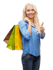 Image showing smiling woman with shopping bags showing thumbs up