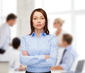 Image showing smiling businesswoman with crossed arms at office