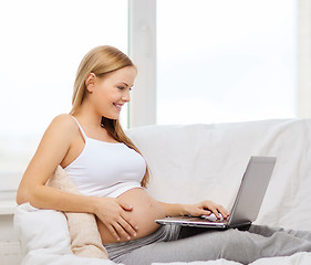 Image showing smiling pregnant woman with laptop computer