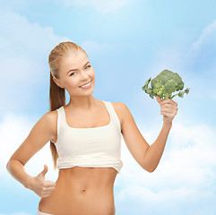 Image showing woman pointing at her abs and holding broccoli