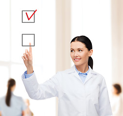 Image showing smiling female doctor pointing checkbox