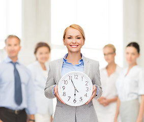 Image showing smiling businesswoman with wall clock