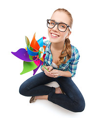 Image showing woman in eyeglasses sitting on floor with windmill