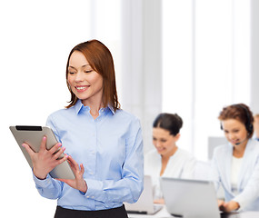 Image showing smiling woman looking at tablet pc at office