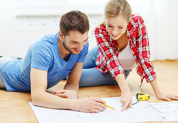 Image showing smiling couple looking at blueprint at home