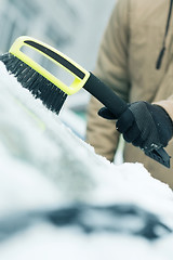 Image showing man cleaning snow from car windshield with brush