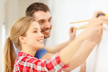 Image showing smiling couple measuring wall