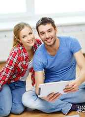 Image showing smiling couple looking at tablet pc at home